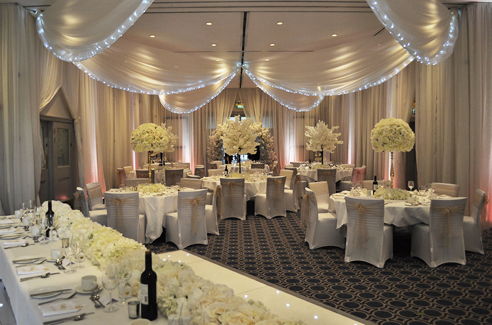 Wedding wall drapes at Bowood Golf Club and Hotel with uplighting and ceiling drapes with fairy lights.