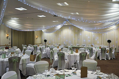 Wedding at the Cotswold Water Park De Vere Hotel, with wall and ceiling drapes, and green chair sashes
