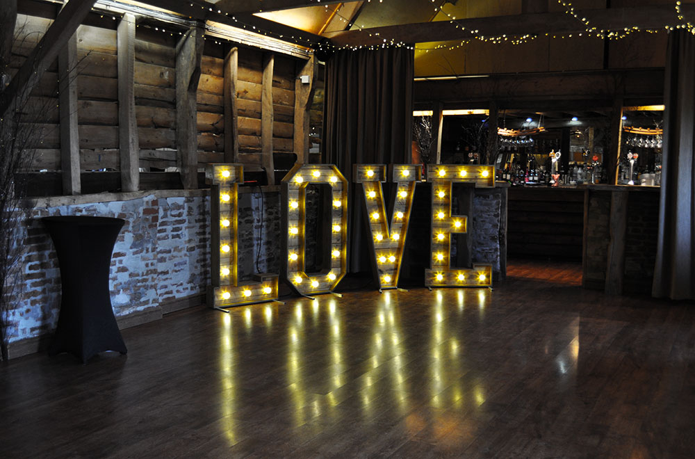 Large Wooden Rustic Love Letters at Wellington barn Wedding venue. With Warm White Fairground style LED bulbs.